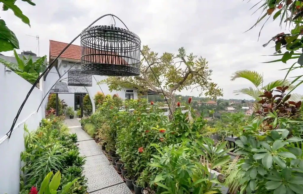 Jalur taman berlantai keramik dengan tanaman pot di sepanjang teras atas villa