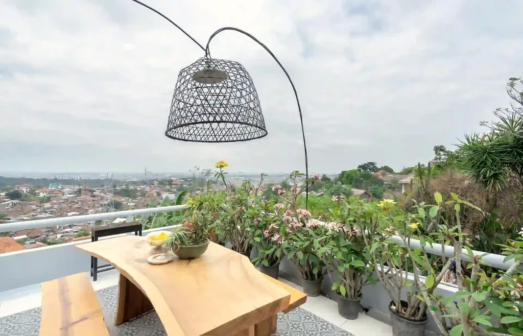 Bangku kayu live-edge di samping tanaman kamboja di teras dengan pemandangan kota panoramik