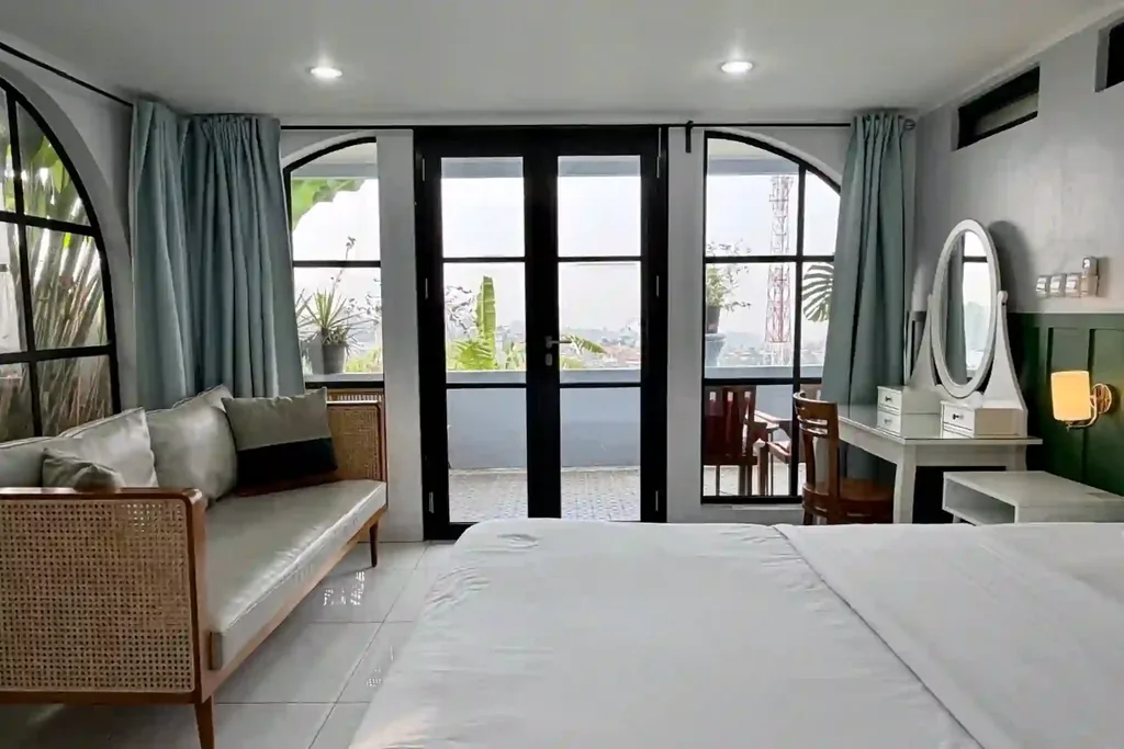Kamar 4 dengan daybed rotan dan pintu Prancis menuju balkon pribadi berpemandangan kota
