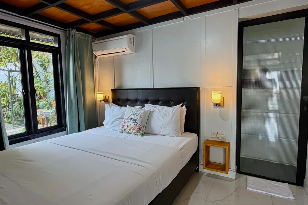 Queen bed Kamar 2 dengan headboard hitam berkancing, AC, dan pintu kamar mandi dalam