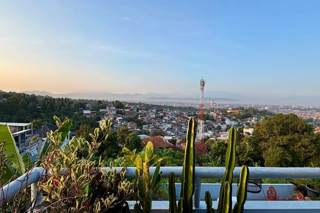 Pemandangan siang hari kota Bandung dan pegunungan dari teras Villa Yucca dengan kaktus di latar depan